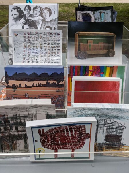 A selection of brightly colored postcards depicting different art are displayed on a stand