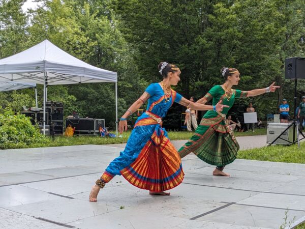 Two dancers in brightly colored costumes pose gracefully as they perform classical Indian dance on Parkfest's main stage